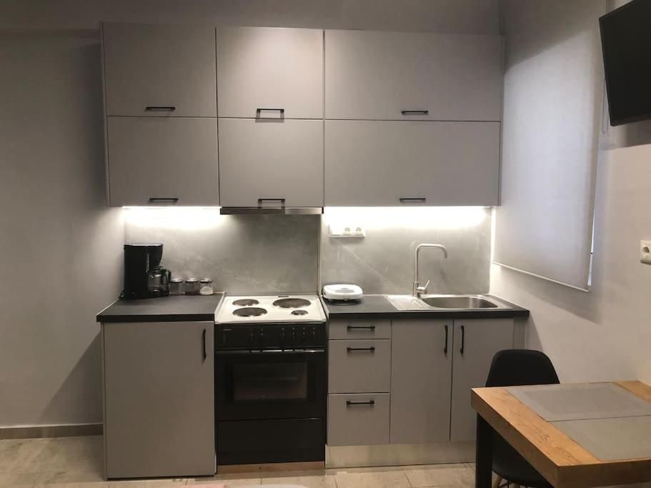 uma cozinha com armários brancos e um forno com placa de fogão em Vv Cosy Host 1 em Lárissa