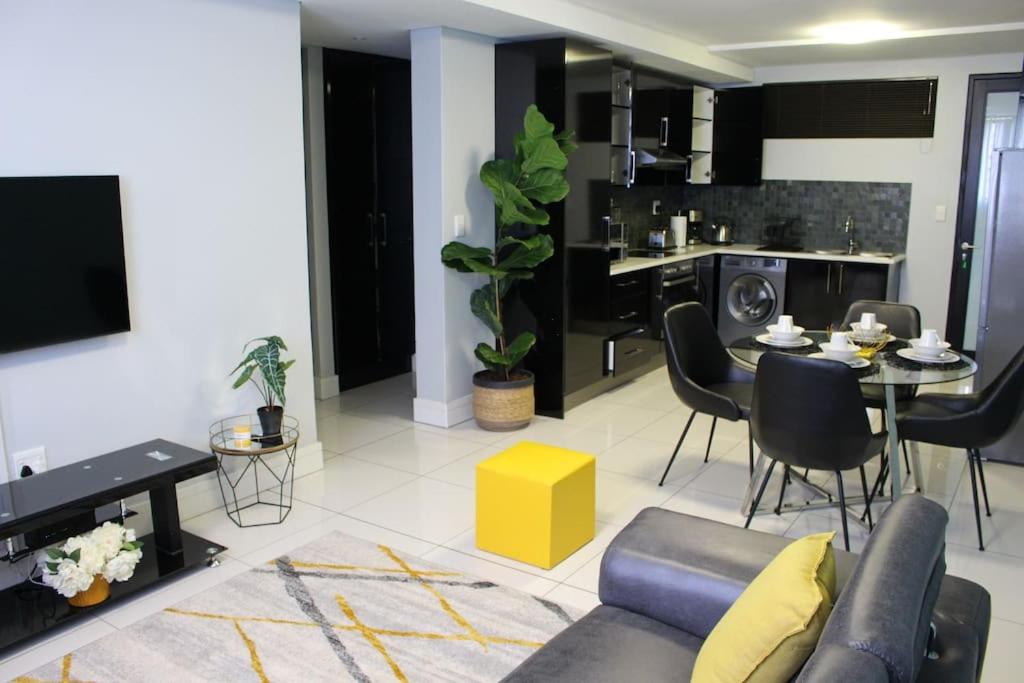 a living room with a couch and a dining room at Favour's 2 Bedroom Apartment on 77 in Windhoek