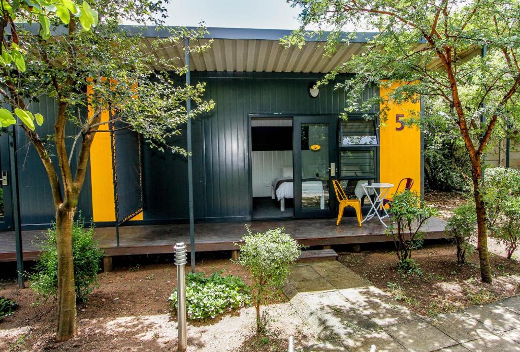 a green and yellow house with a wooden porch at SleepOver Lanseria in Lanseria