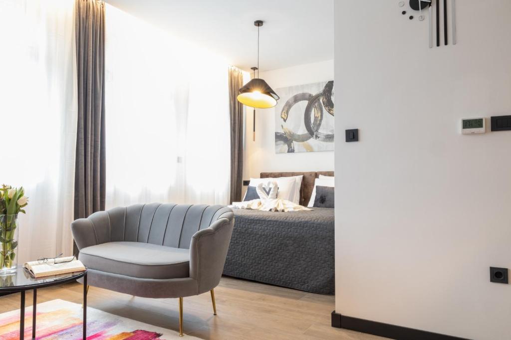 ein Wohnzimmer mit einem Stuhl und einem Bett in der Unterkunft Apartmani Mozart-centar Virovitica in Virovitica