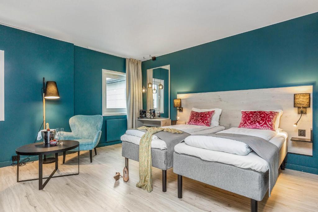 1 dormitorio con paredes azules, 1 cama y 1 silla en Thon Partner Hotel Central en Elverum