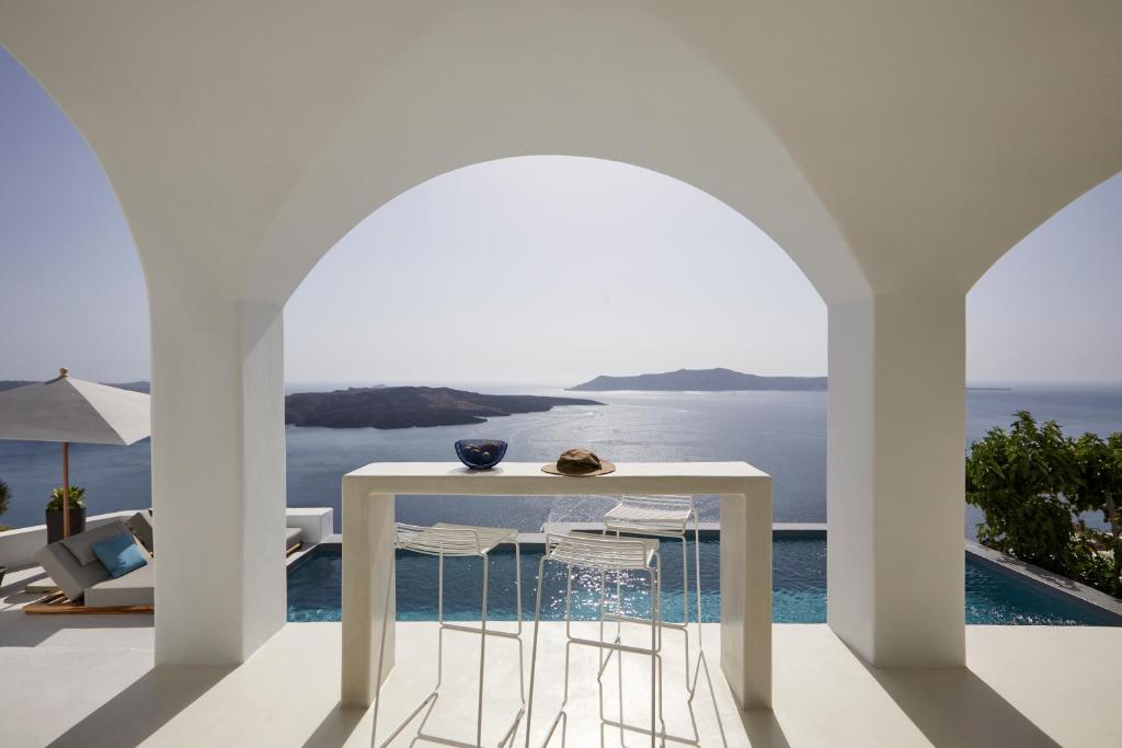 a white table with chairs and a view of the ocean at Inspire Santorini Luxury Villas in Fira