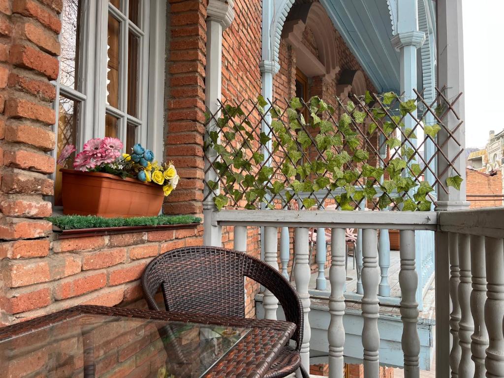 una silla de mimbre en un porche con ventana en Cozy Apartment, en Tiflis