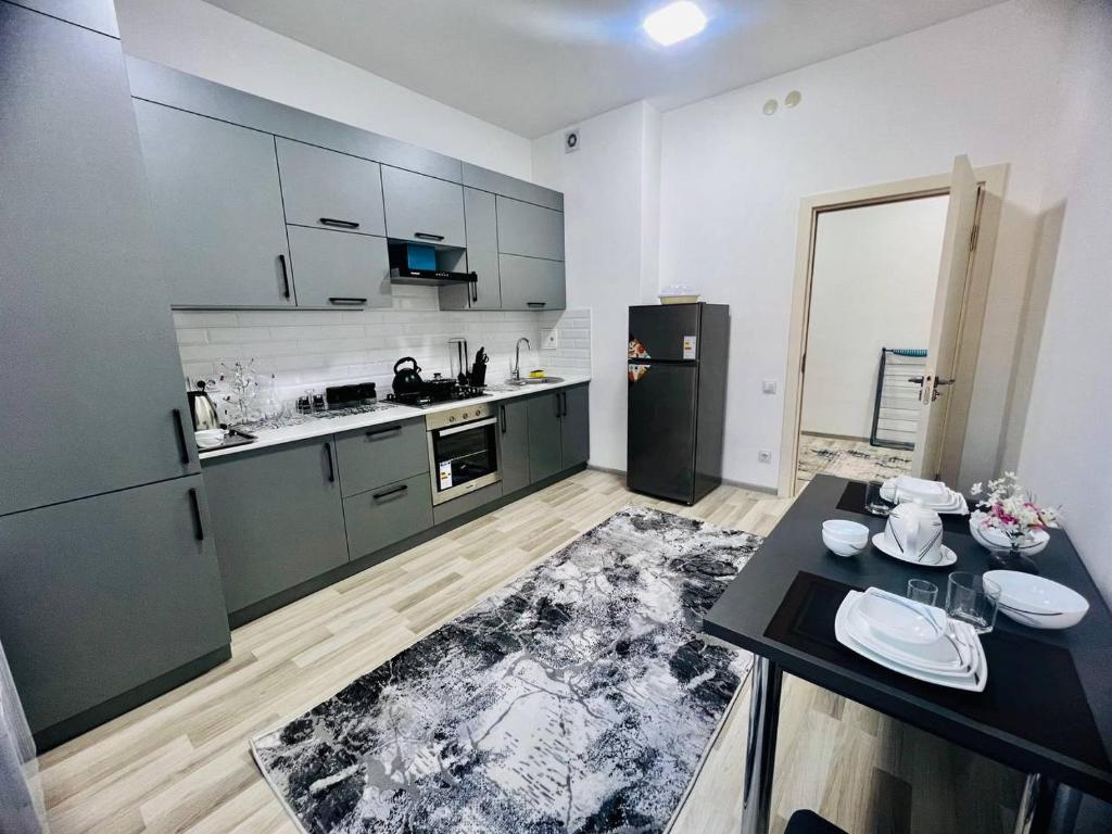 een keuken met roestvrijstalen apparatuur en een zwarte tafel bij Comfort apartment in Tasjkent