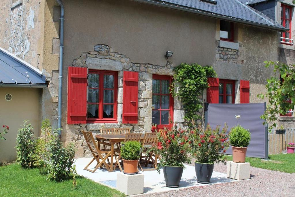 un patio con persianas rojas y una mesa con plantas en Gîte Savauldetour, en Ouroux