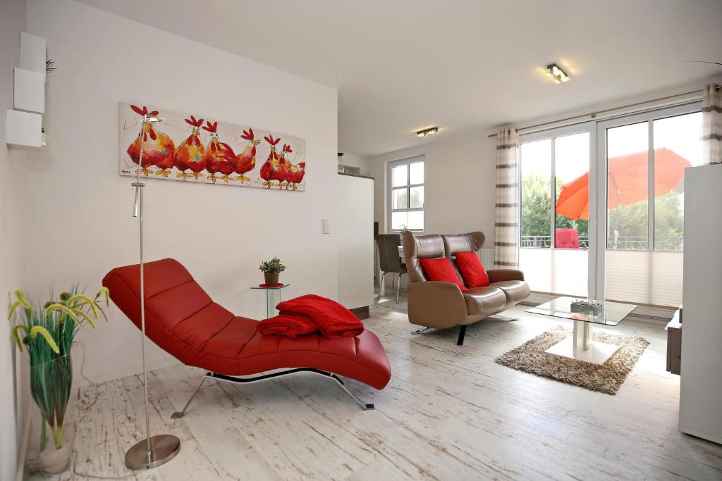 - un salon avec une chaise rouge et un canapé dans l'établissement Residenz von Flotow Wohnung 13, à Heiligendamm