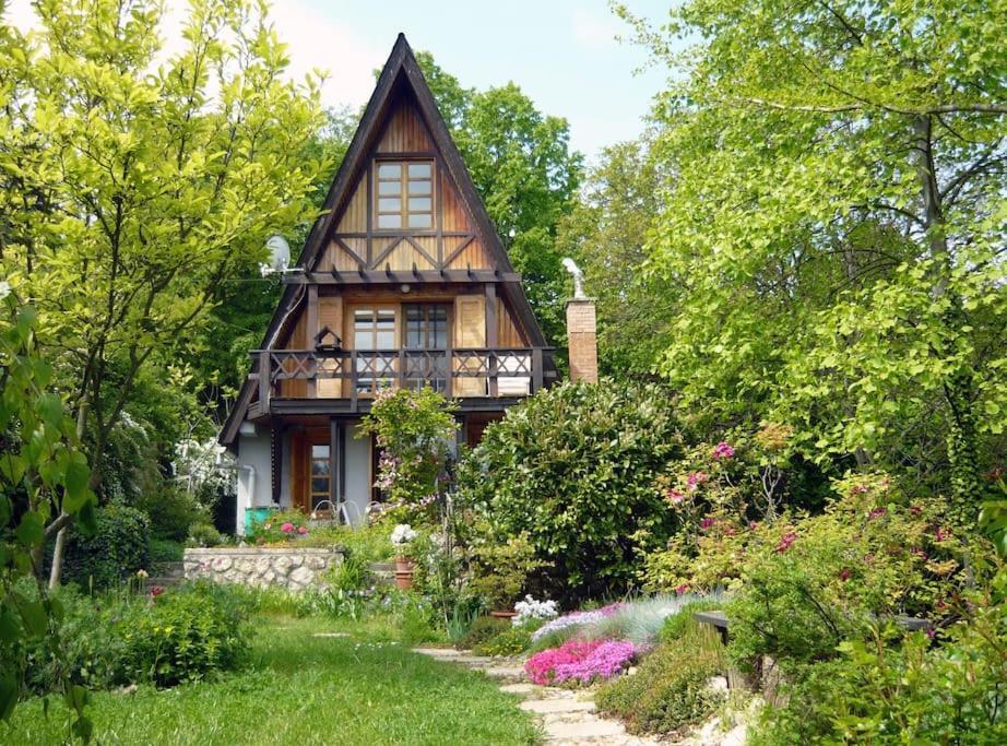 uma pequena casa com um jardim em frente em Erdő Lelke Vendégház: mesebeli, erdőszéli faház panorámával em Nagymaros