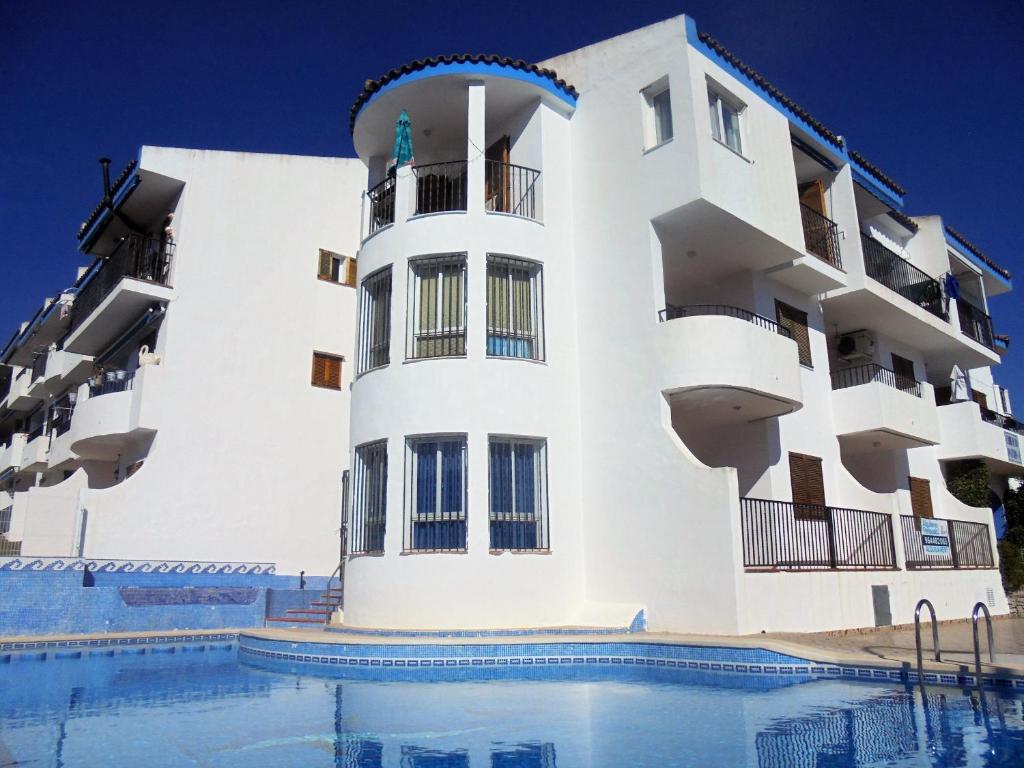 um edifício branco com uma piscina em frente em Patios I em Peñíscola