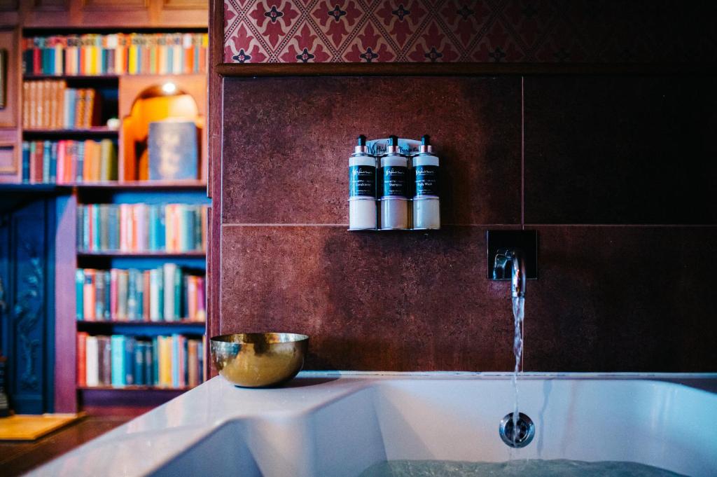 uma banheira num quarto com uma estante de livros em The George Hotel em Inveraray
