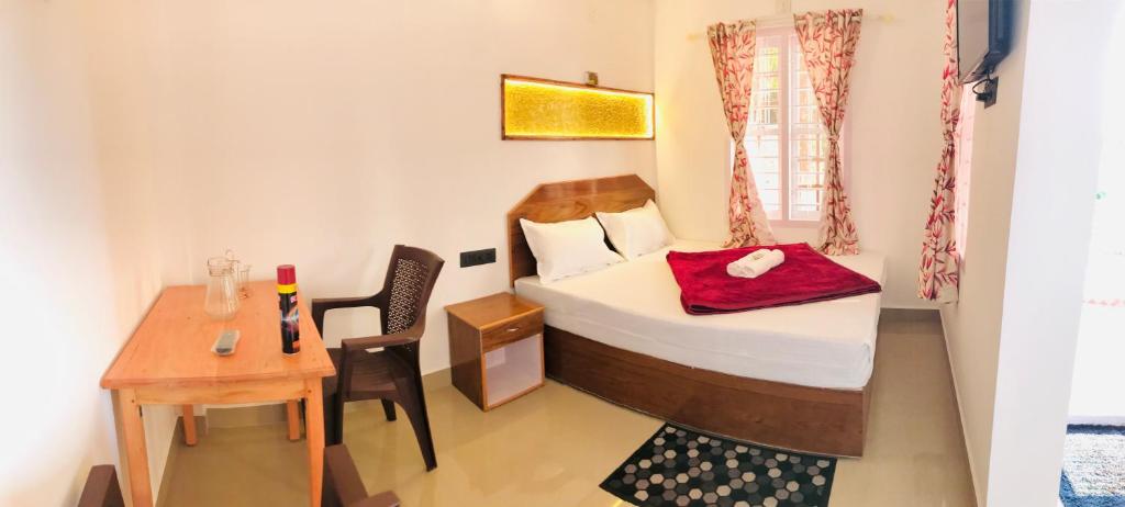 a small room with a bed and a table at Drizzle Valley Cottage in Munnar