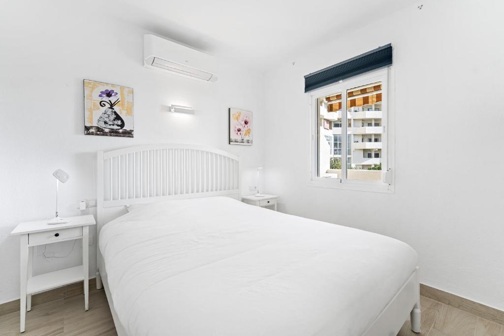 ein weißes Schlafzimmer mit einem weißen Bett und einem Fenster in der Unterkunft Benalbeach Sea View in Benalmádena