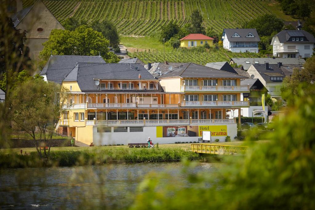 - un grand bâtiment à côté d'une étendue d'eau dans l'établissement Panorama Hotel & Restaurant, à Kröv