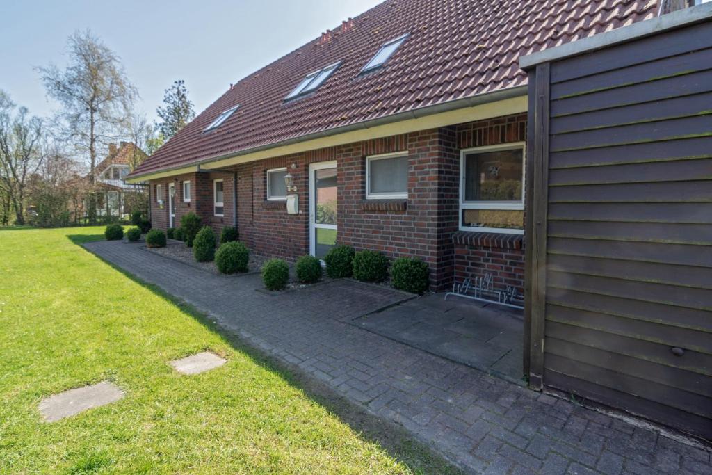 a red brick house with a sidewalk next to a yard at Ferienhaus Seewind 11/1 in Werdum