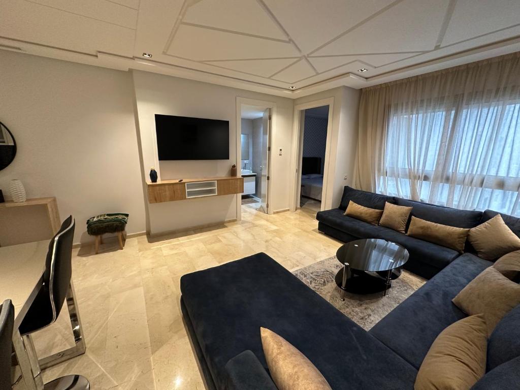 Una sala de estar con un sofá azul y un televisor en Le LUXE EN BORD DE MER, en Tánger