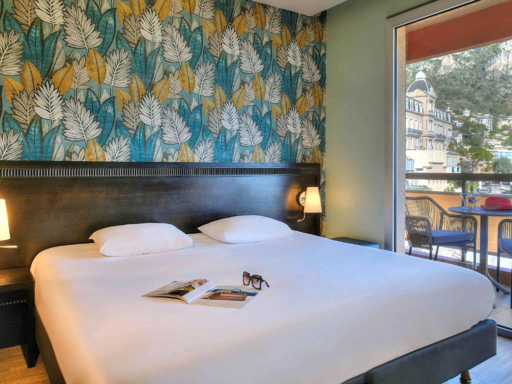 a bedroom with a large bed with a book on it at ibis Styles Beaulieu sur Mer in Beaulieu-sur-Mer