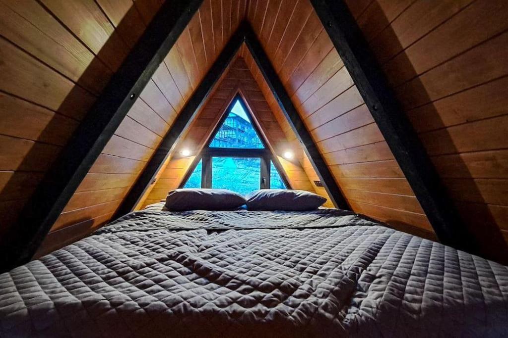 Łóżko w drewnianym pokoju z oknem w obiekcie Mirador Cottage w Sławsku
