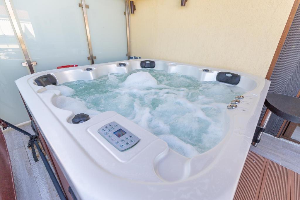 a jacuzzi tub with a thermometer in it at Casa Luxury Wellness Apartman By BLTN in Siófok