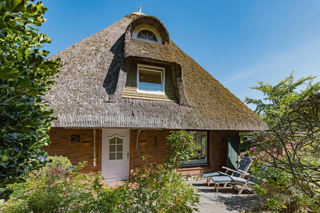 a thatch roofed house with a bench and a window at Fischers Koje in List
