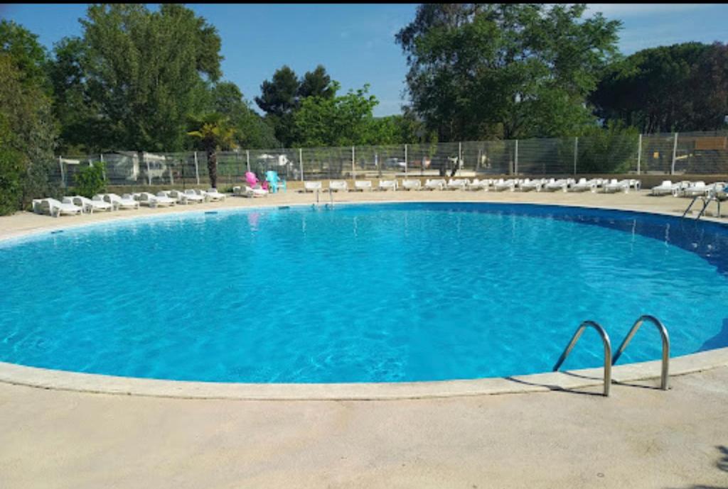 a large blue swimming pool with chairs and a fence at Au p’tit bonheur in La Roque-dʼAnthéron