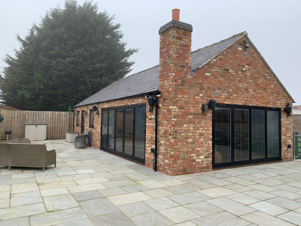 a brick building with large windows and a patio at Luxury Studio Cottage at Foot of Yorkshire Wolds in York