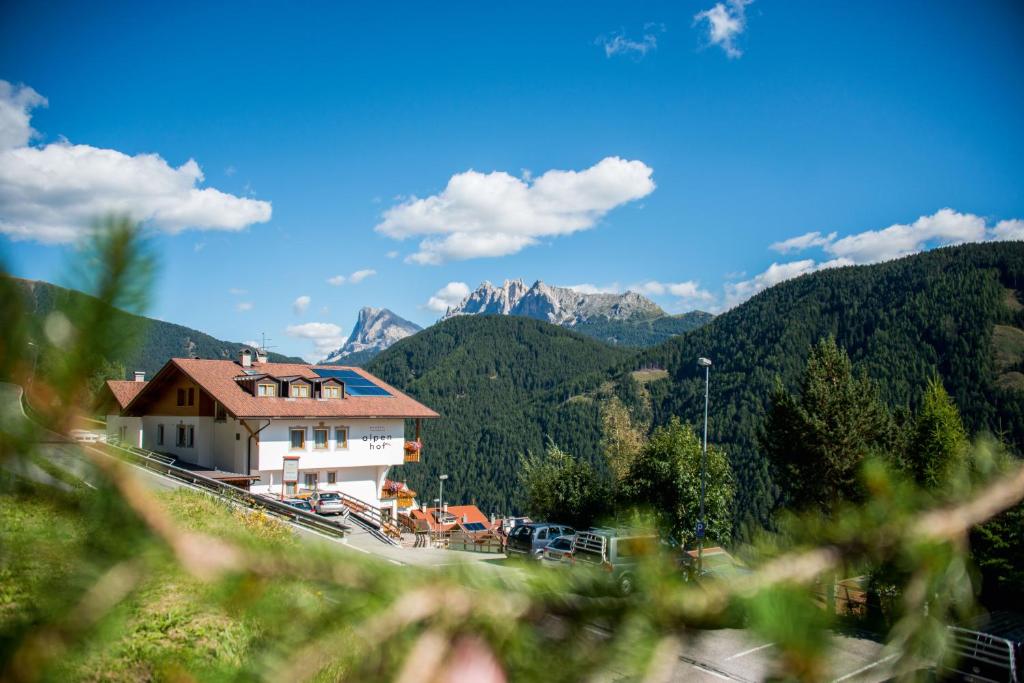 una casa en una colina con montañas en el fondo en MOUNTAIN RESIDENCE ALPENHOF - company Hotel Alpenhof KG sas der Gasser Renate, en Bresanona