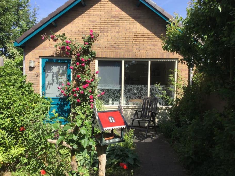 a house with a bench and flowers in front of it at Cottage Egmond-Binnen met besloten tuin in Egmond-Binnen