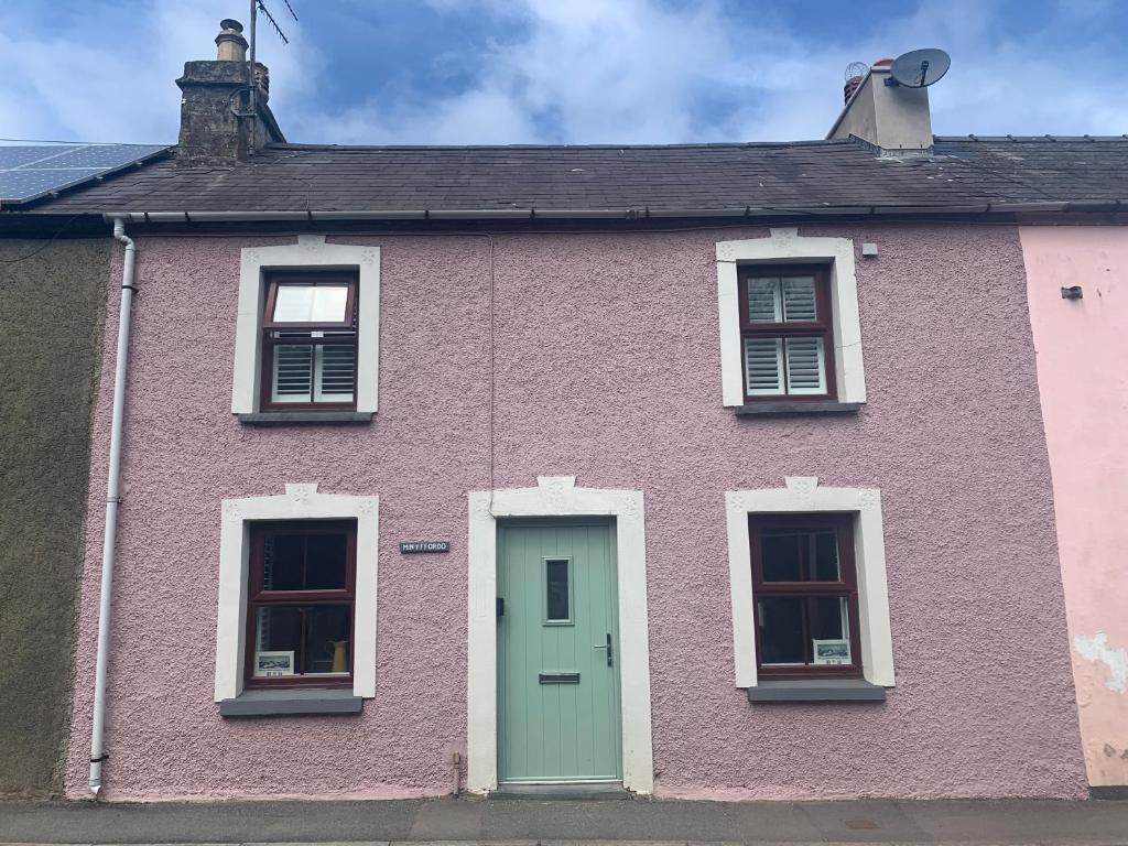 a pink house with a green door and windows at Min-Y-Fford sleeps 6 plus pet in Newport Pembrokeshire