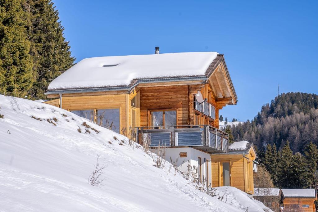 ein Holzhaus auf einem schneebedeckten Hügel in der Unterkunft Chalet Elsa in Riederalp