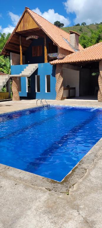 a blue swimming pool in front of a house at Chalé Mantiqueira in Piranguçu