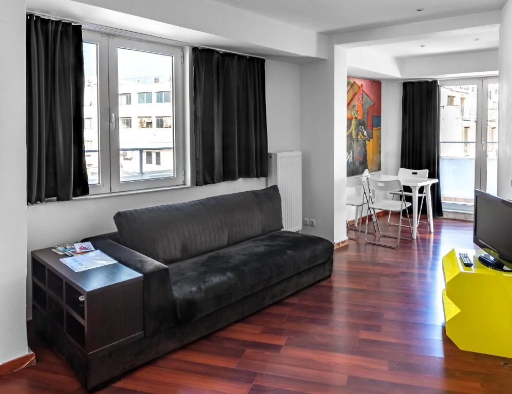 a living room with a black leather couch and a television at Loft in Athens