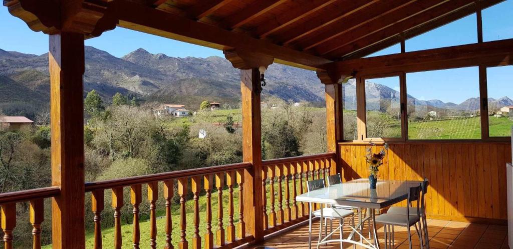 een veranda met een tafel en stoelen en bergen bij Casa Vacacional Mari Paz in Llanes