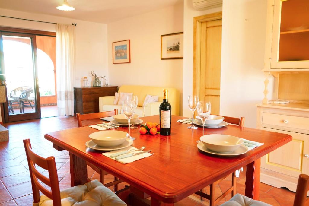 una sala da pranzo con tavolo e bottiglia di vino di Mereu Central Apartment a Villasimius