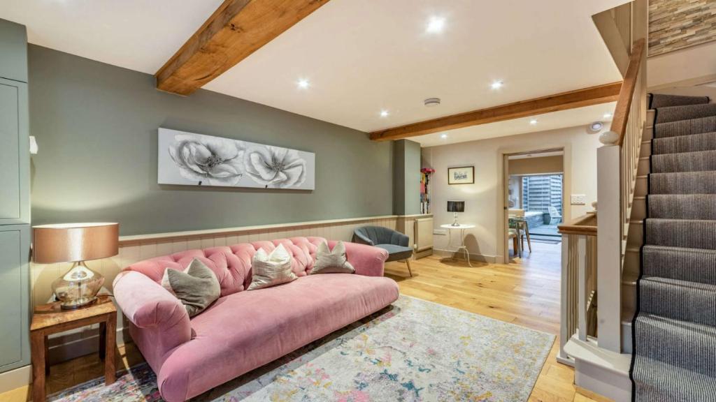 a living room with a pink couch and stairs at Church View Apartment in Stow on the Wold