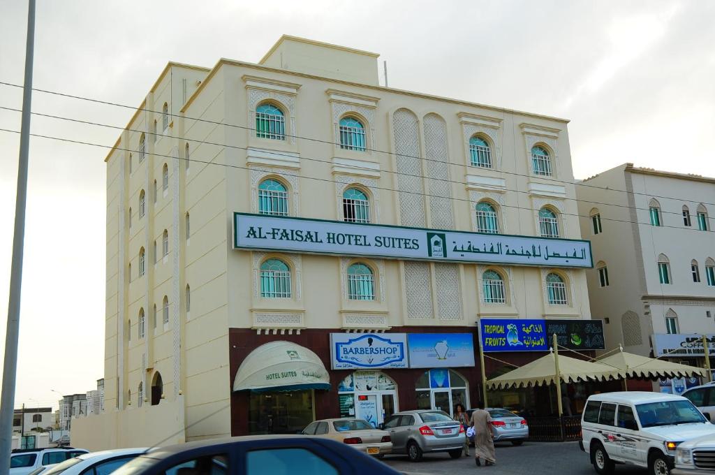 un grand bâtiment avec des voitures garées devant lui dans l'établissement Al Faisal Hotel Suites, à Sour