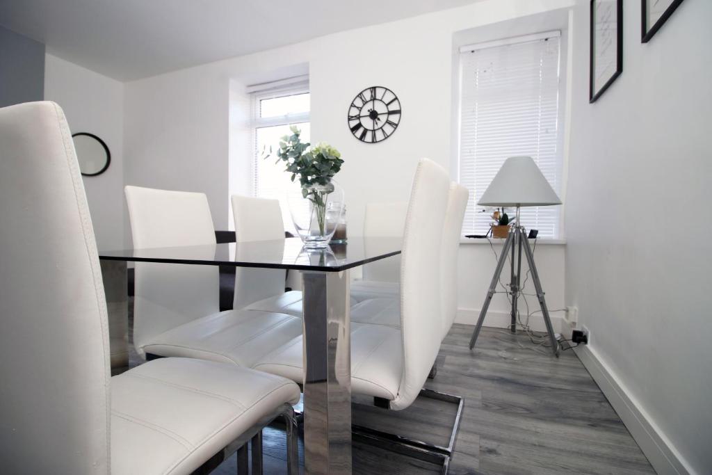 a dining room with a glass table and white chairs at Executive Style 2 Bed Flat in Bridgend F2 in Bridgend