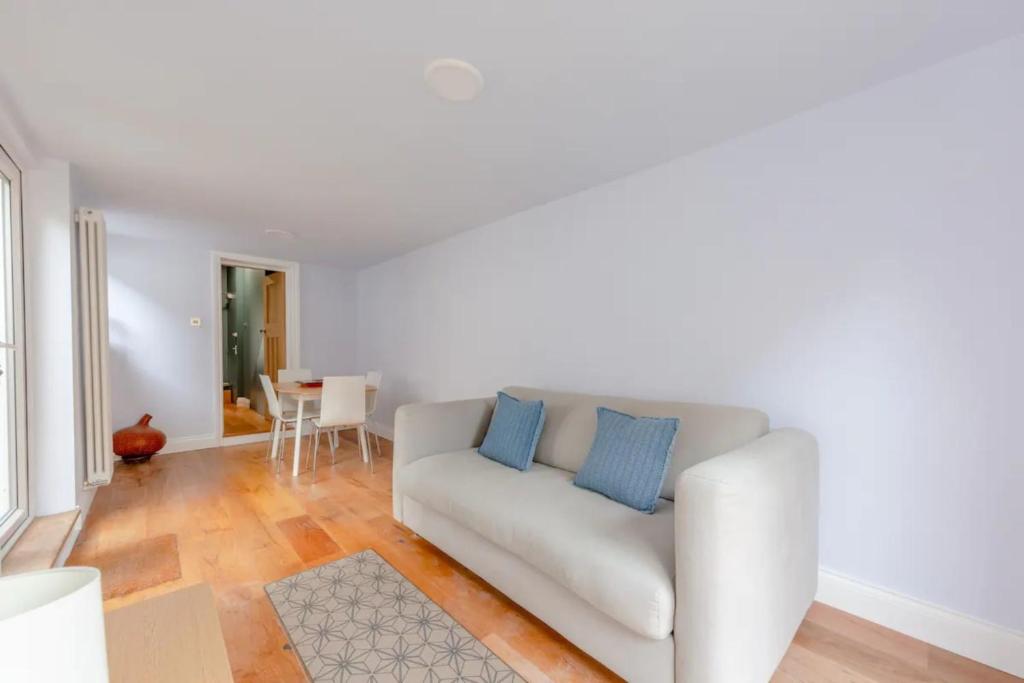 - un canapé blanc avec des oreillers bleus dans le salon dans l'établissement Tranquil 1 Bedroom Flat in Peckham, à Londres