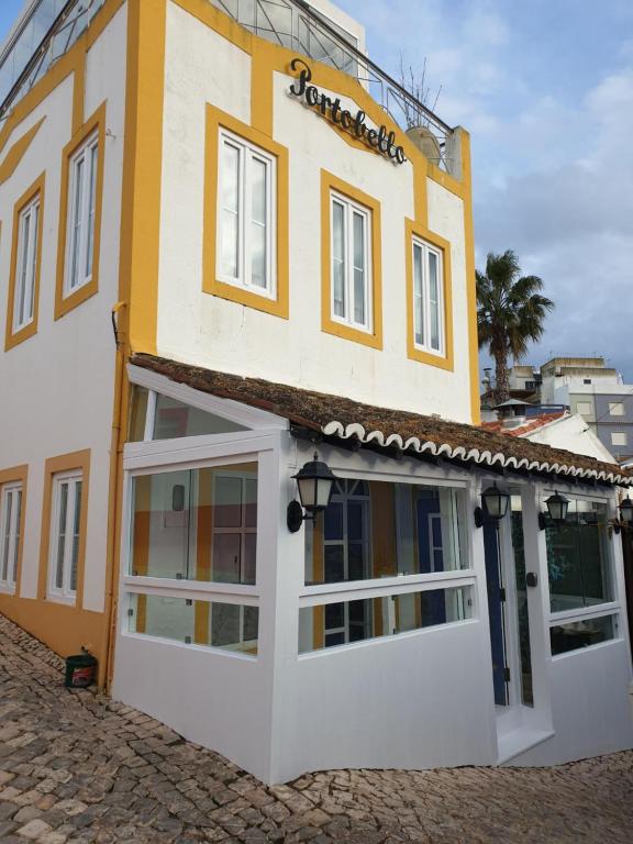 a yellow and white building with white doors at Portobello River and Sea View in Alvor