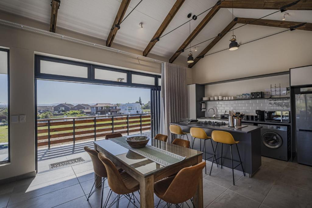 a kitchen with a table and chairs and a large window at Kabeljauws Beach Apartments in Jeffreys Bay