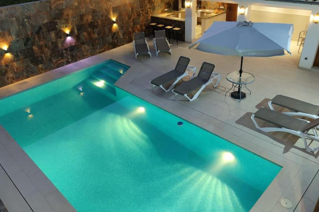 a swimming pool with chairs and an umbrella at Casa El Rafal in Porreres