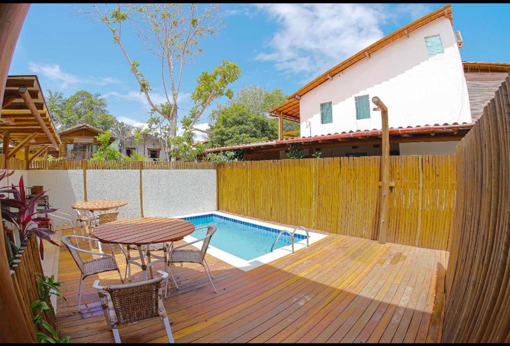 a wooden deck with a table and chairs next to a pool at Flat Vila Taipu in Marau