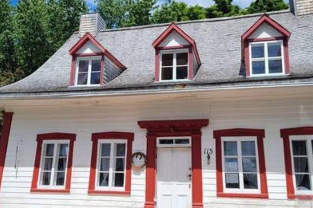Maison blanche avec parure rouge et porte blanche dans l'établissement Om chalet 1 avec spa face au fleuve, à Saint-Jean