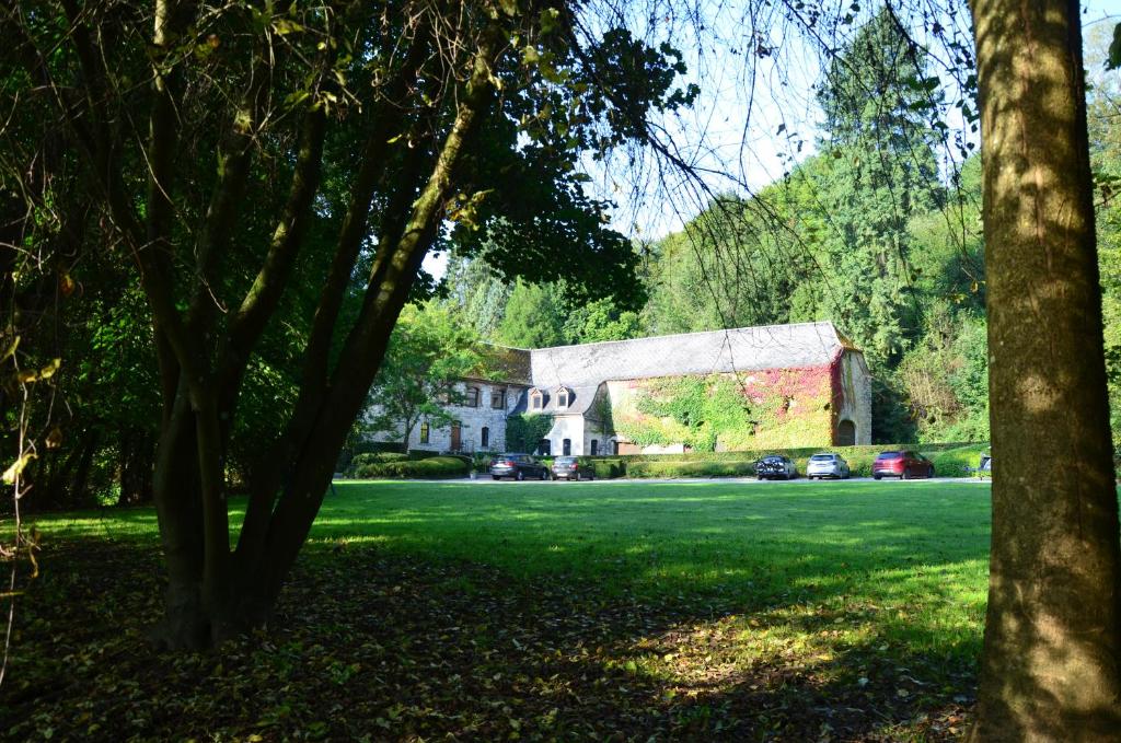 une grande maison blanche avec une grange et des arbres dans l'établissement Hotel Le Moulin Des Ramiers, à Crupet