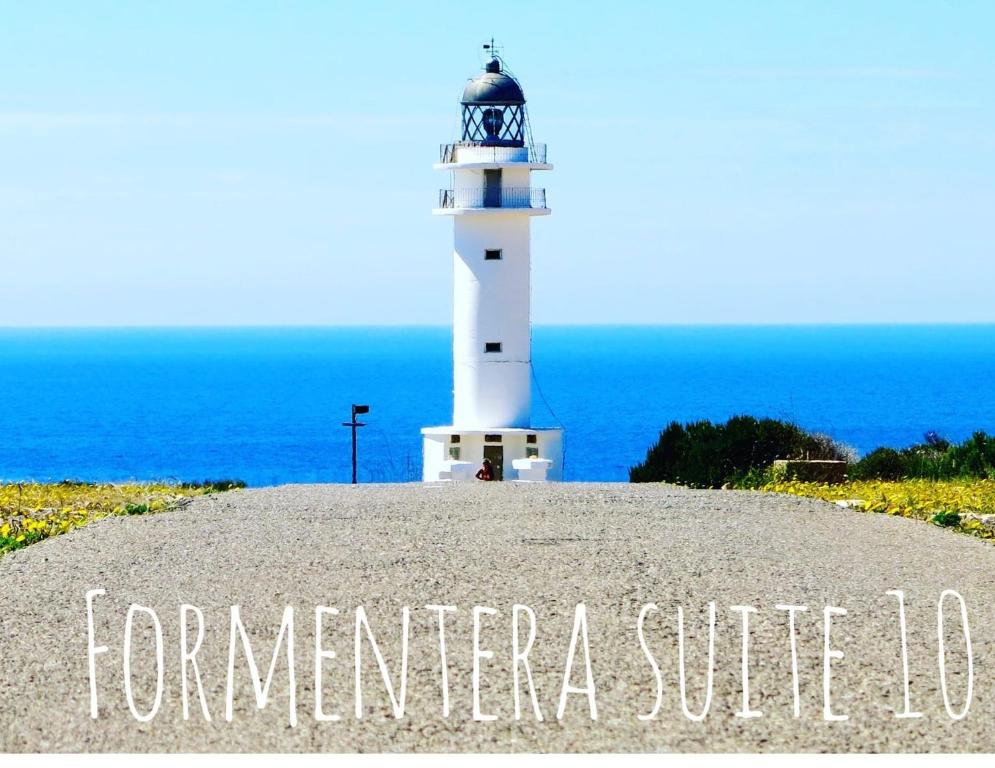 un faro sentado en la cima de una colina con el océano en Formentera Suite 10 en Es Pujols
