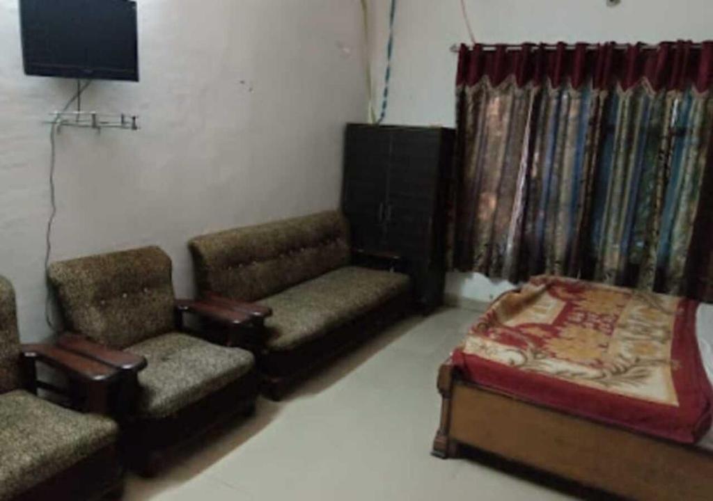 ein Wohnzimmer mit einem Sofa, einem Bett und Stühlen in der Unterkunft Hotel M. S. Palace By WB Inn in Agra