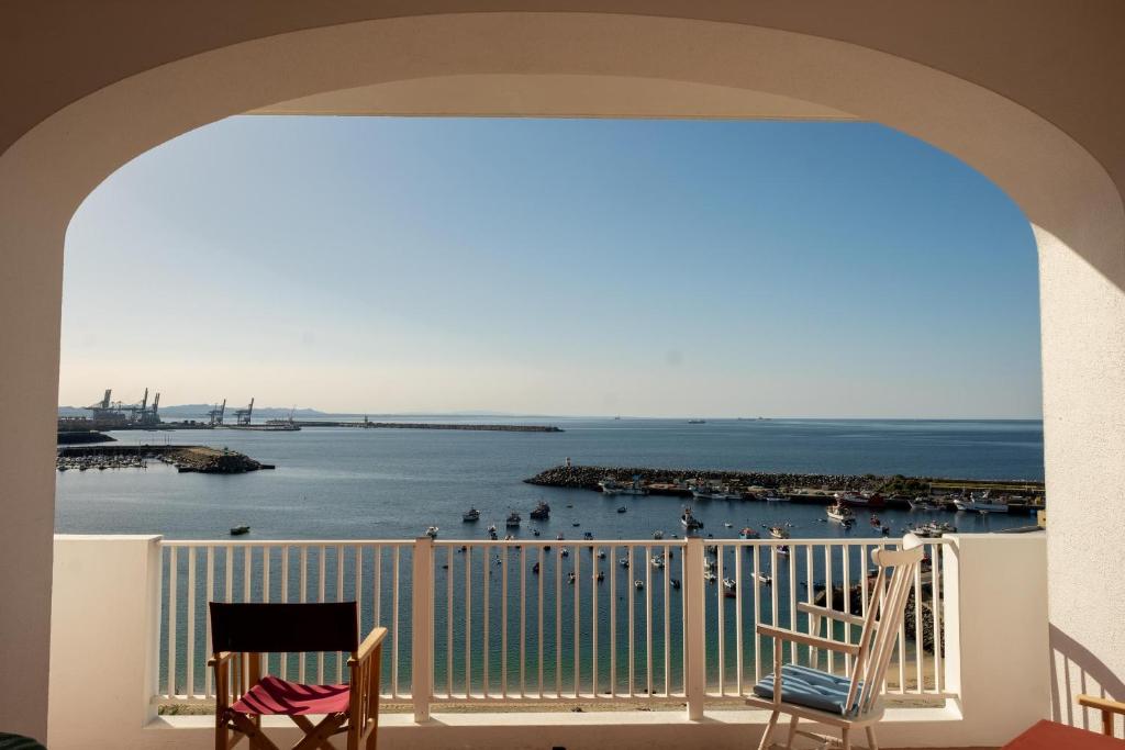 a balcony with two chairs and a view of the water at Manas Coliving in Sines