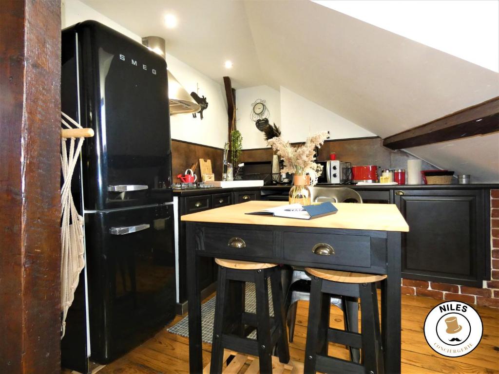 a kitchen with a black refrigerator and a table with stools at La Caze Paloise ~ Atypique ~ 100% Fonctionnel in Pau