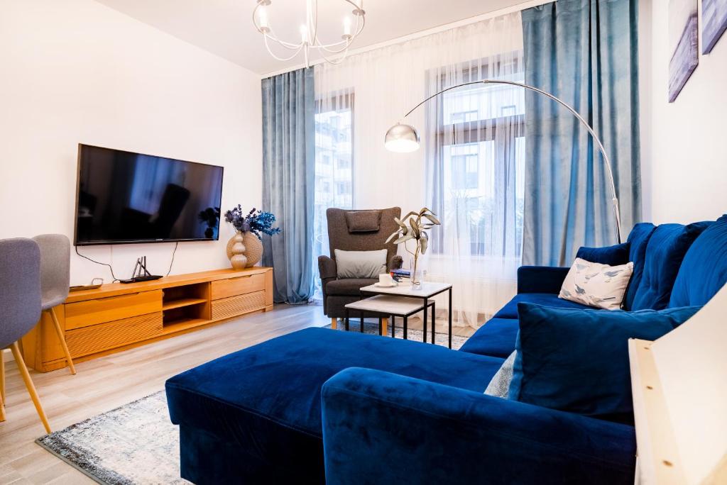 un salon avec un canapé bleu et une télévision dans l'établissement ApartamentySnu, Jagielloński Premium, Centrum, à Radom