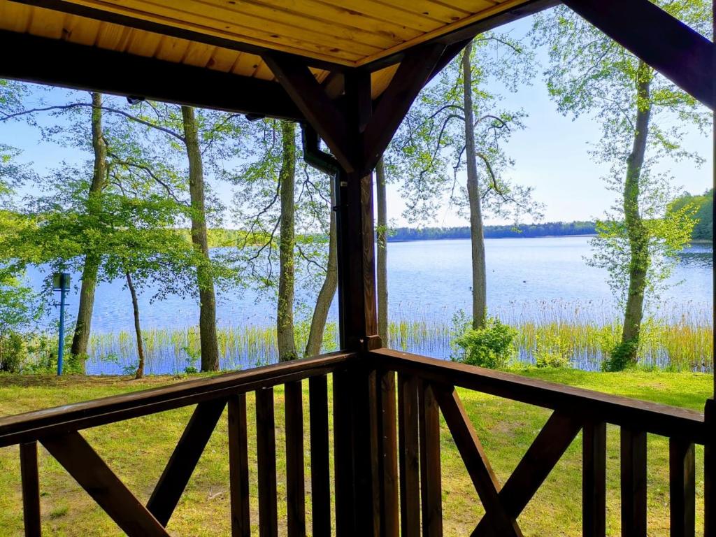 vistas al lago desde el porche de una cabaña en Kujanki - domki z widokiem na jezioro, en Zakrzewo