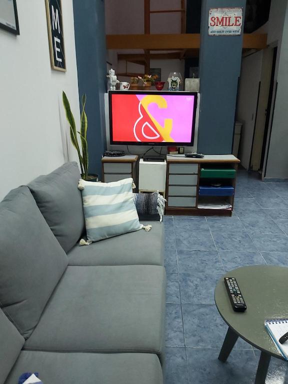 sala de estar con sofá gris y TV en Cerca de todo monoambiente en Buenos Aires