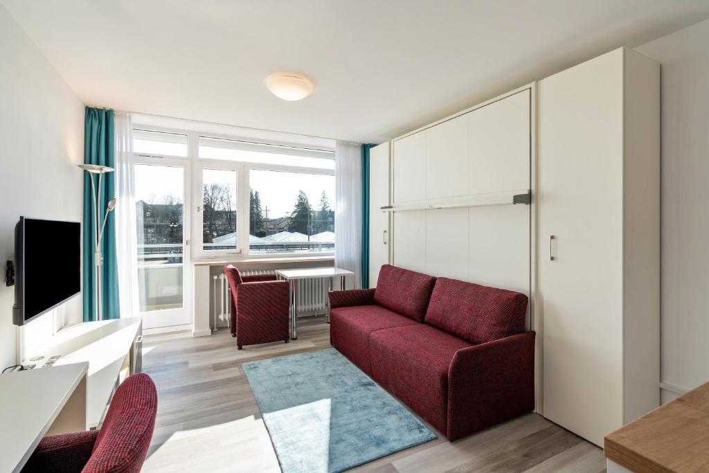 a living room with a red couch and chairs at Huber Living Basic 105 in Germering